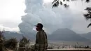 Seorang warga setempat duduk di bangku kayu sambil melihat Gunung Bromo yang sedang erupsi di Ngadisari, Probolinggo, Jawa Timur, Selasa (5/1/2016). (REUTERS/Darren Whiteside)