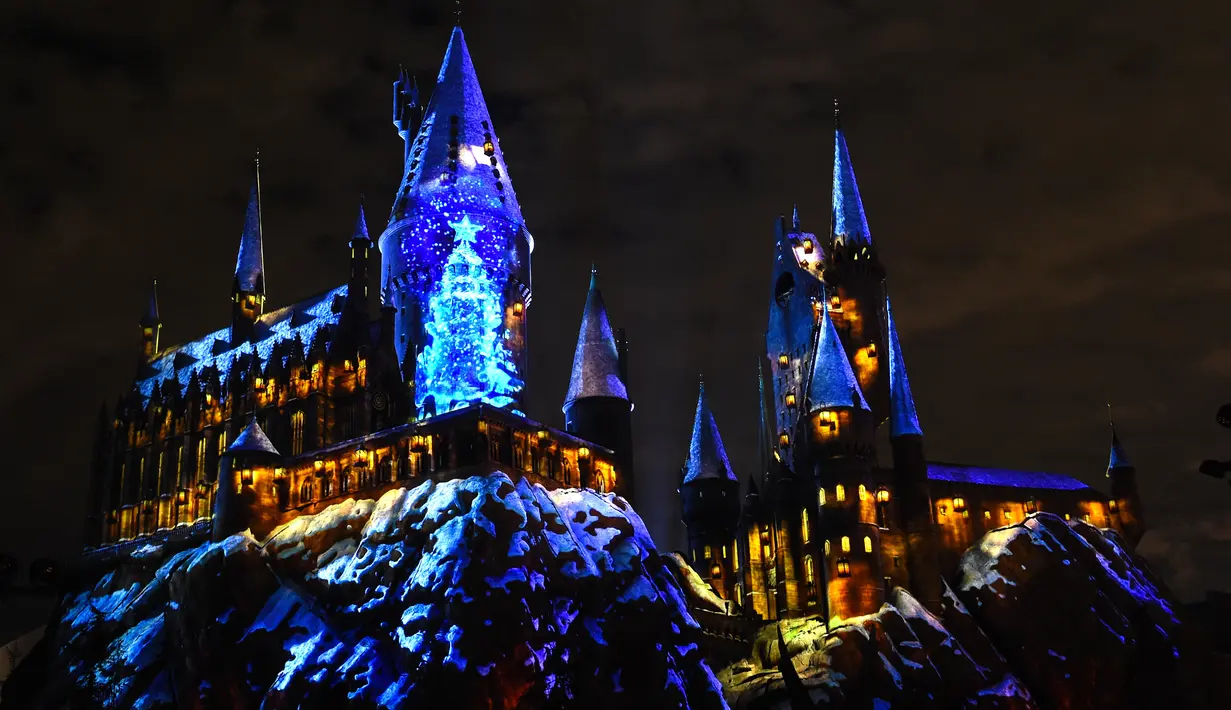 Cahaya warna-warni menghiasi kastil Dunia Harry Potter dihiasi cahaya biru di Universal Studios Hollywood, Universal City (16/11). Pertunjukan ini bertemakan 'The Magic of Christmas at Hogwarts Castle'. (AFP Photo/Chris Delmas)