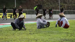 Namun dibalik semua itu ada beberapa visual yang menari untu disimak. Salah satunya  kebahagian warga lokal yang sedang merapihkan rumput di area Sirkuit Internasional Mandalika agar terlihat lebih indah dan asri. (AP Photo/Achmad Ibrahim)