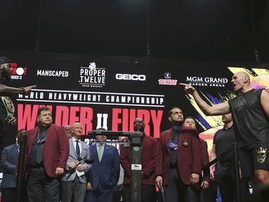Petinju asal Inggris, Tyson Fury (kanan) menunjuk ke arah Deontay Wilder dari AS saat melakukan penimbangan berat badan untuk pertandingan tinju kelas berat WBC di Las Vegas (21/2/2020).  Tyson Fury dan Deontay Wilder akan bertanding di MGM Arena. (AP Photo/Isaac Brekken)