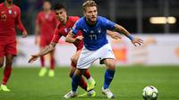 Striker Italia, Ciro Immobile membawa bola dari kawalan bek Portugal, Joao Cancelo selama pertandingan UEFA Nations League di Stadion San Siro di Milan (17/11). Italia bermain imbang 0-0 atas Portugal. (AFP Photo/Marco Bertorello)