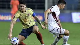 Gelandang Kolombia, James Rodriguez, berebut bola dengan bek Venezuela, Ronald Hernandez, pada laga kualifikasi Piala Dunia 2022 zona Amerika Selatan di Estadio Metropolitano, Sabtu (10/10/2020) pagi WIB. Kolombia menang 3-0 atas Venezuela. (AFP/Gabriel Aponte/pool)