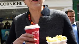 PM Inggris, Theresa May bereaksi sambil membawa keripik dan minuman saat berhenti untuk kampanye di Mevagissey, Cornwall, Selasa (2/5). Foto ini menjadi perbincangan karena Theresa May terlihat konyol saat mengemil. (Dylan Martinez/PA via AP)