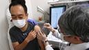 Seorang pria (kiri) menerima dosis ketiga vaksin COVID-19 Pfizer di Nagoya, prefektur Aichi, Rabu (1/12/2021). Jepang mulai memberikan suntikan booster COVID-19 kepada petugas medis di tengah kekhawatiran atas varian omicron yang telah terdeteksi di negara itu. (STR /JIJI PRESS/ AFP)