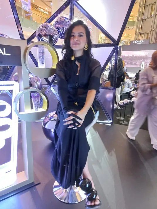 Eva Celia tampil sedikit gothic dengan kemeja transparan dan rok hitam. Dilengkapi dengan aksen belt rantai dan peniti serta scarf.