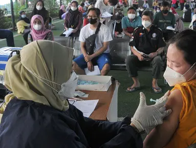 Vaksinator menyuntikkan vaksin dosis ketiga kepada seorang perempuan di kolong flyover Ciputat, Tangerang Selatan, Sabtu (2/4/2022). Selain untuk melengkapi vaksin COVID-19, booster menjadi syarat perjalanan mudik lebaran tahun 2022. (merdeka.com/Arie Basuki)