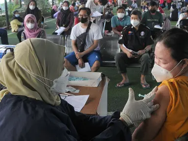 Vaksinator menyuntikkan vaksin dosis ketiga kepada seorang perempuan di kolong flyover Ciputat, Tangerang Selatan, Sabtu (2/4/2022). Selain untuk melengkapi vaksin COVID-19, booster menjadi syarat perjalanan mudik lebaran tahun 2022. (merdeka.com/Arie Basuki)