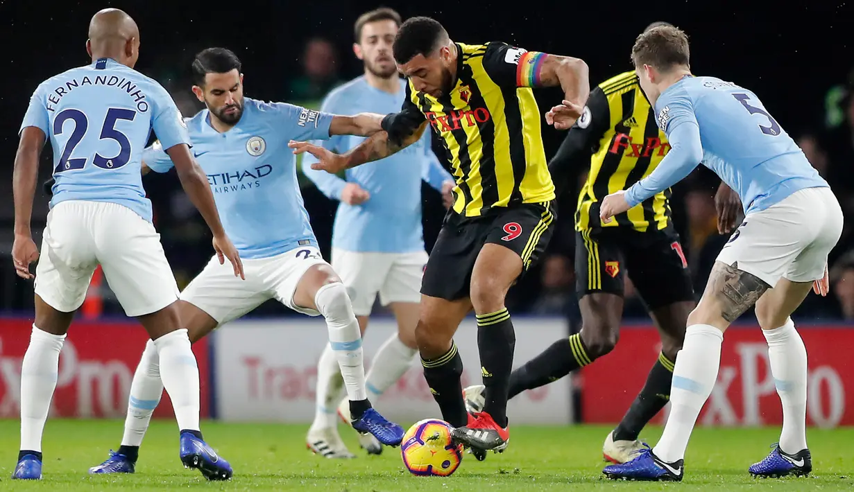 Penyerang Watford, Troy Deeney mengontrol bola dari kawalan tiga pemain Manchester City saat bertanding pada lanjutan Liga Inggris di stadion Vicarage Road (4/12). City menang tipis atas Watford 2-1. (AP Photo/Frank Augstein)