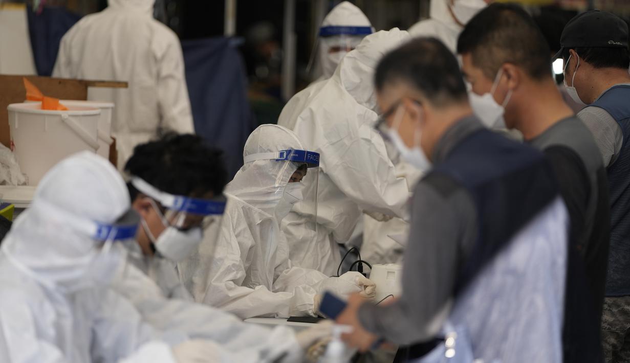 Petugas kesehatan yang mengenakan alat pelindung membantu pengunjung yang mengantre untuk mendapatkan tes virus corona di klinik skrining sementara virus corona di Seoul, Korea Selatan, Jumat (24/9/2021). (AP Photo/Lee Jin-man)