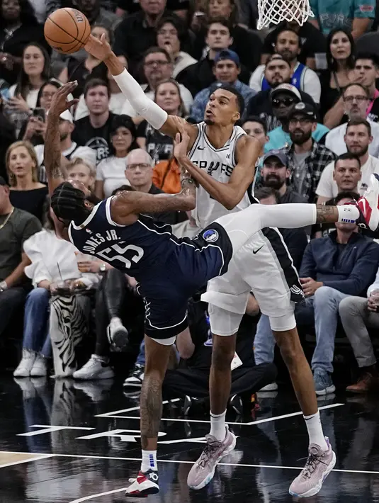 Pebasket San Antonio Spurs, Victor Wembanyama (kanan) berusaha merebut bola dari pebasket Dallas Mavericks, Derrick Jones Jr. pada laga pertama NBA musim 2023/2024 di AT&T Center in San Antonio, Texas, Kamis (27/10/2023). Wembanyama bermain selama 23 menit dengan mencetak 15 poin dan 5 rebound. (AFP/Chandan Khanna)