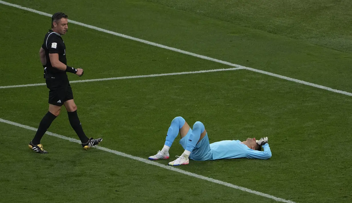 Wasit Raphael Claus (kiri) menyaksikan kiper timnas Iran Alireza Beiranvand terbaring di tanah usai mengalami cedera saat pertandingan sepak bola grup B Piala Dunia Qatar 2022 antara Inggris dan Iran di Stadion Internasional Khalifa, Doha, Qatar, Senin (21/11/2022). Meski mengalami cedera yang cukup parah, Beiranvand masih sempat berdiri dan mencoba melanjutkan pertandingan. (AP Photo/Pavel Golovkin)