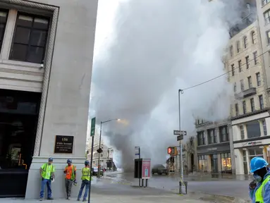 Sebuah pipa uap meledak menyebabkan gumpalan besar asap putih mengepul ke udara di Distrik Flatiron, Manhattan, Kamis (19/7). Pipa uap  yang dipasang di bawah Fifth Avenue dan 21st Street tersebut meledak pada pagi waktu setempat. (AP Photo/Richard Drew)