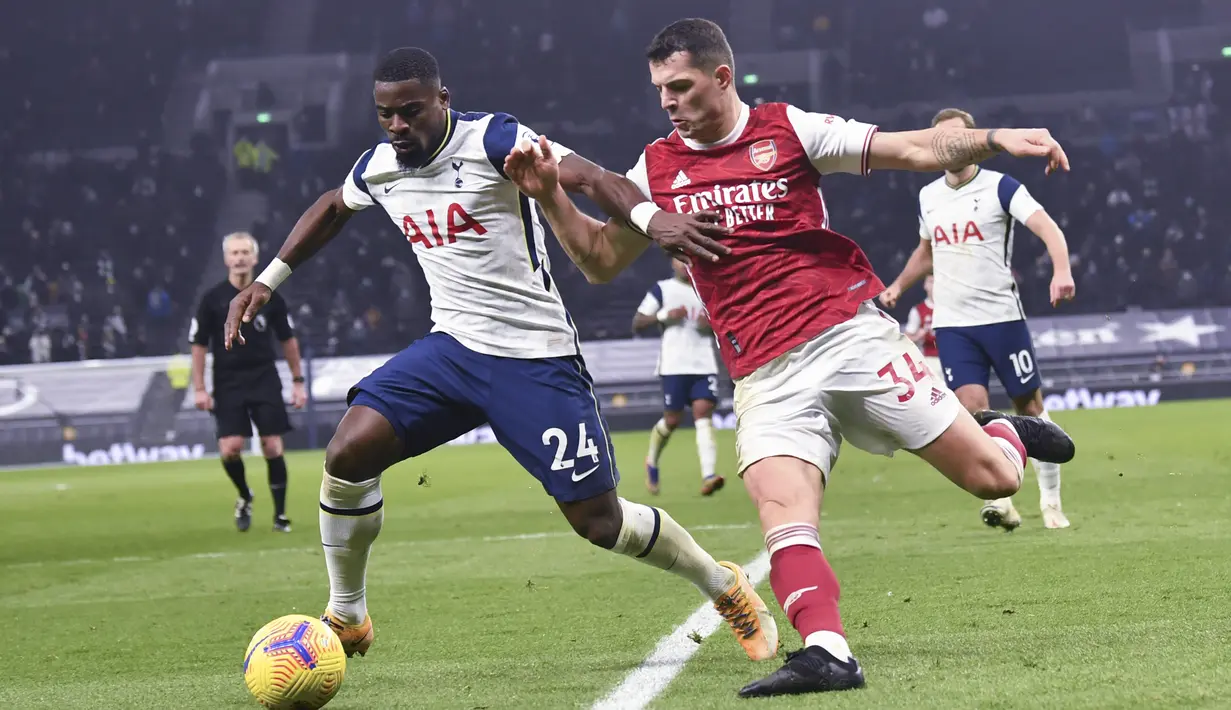 Bek Tottenham Hotspur, Serge Aurier membawa bola dari kejaran gelandang Arsenal, Granit Xhaka pada pertandingan lanjutan Liga Inggris di Tottenham Hotspur Stadium di London, Inggris , Minggu (7/12/2020). Tottenham menang 2-0. (Glyn Kirk/Pool via AP)