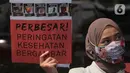 Seorang wanita dari Massa Aliansi Kompak menujukkan poster tuntutan di depan Kemenkes, Jakarta, Kamis (26/11/2020). Aksi bertujuan untuk memberikan surat somasi kedua untuk segera menyelesaikan revisi Peraturan Pemerintah No. 109 Tahun 2012 (PP 109/2012). (Liputan6.com/Herman Zakharia)