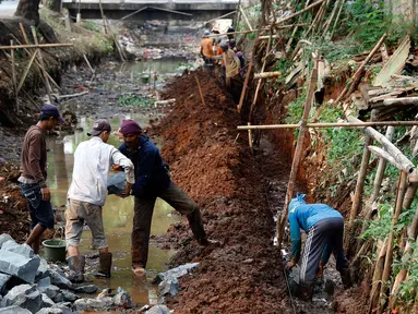 Pekerja mengerjakan pondasi turap di bantaran kali Tanah Baru, Srengseng Sawah, Jakarta Selatan, Jumat (9/10/2015). Pengerjaan turap ini bertujuan untuk mengatasi kelongosoran tanah di pinggiran kali. (Liputan6.com/Yoppy Renato)