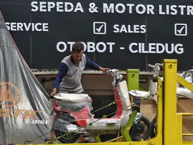 Pekerja tengah menurunkan sepeda motor listrik yang akan di jual di shorum di Tangerang, Banten, Kamis (27/7/2023). (Liputan6.com/Angga Yuniar)