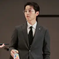 Mengenakan setelan jas rapi serta sepasang kacamata, Yoon Hyun Woo tampak tenang bahkan saat ia berurusan dengan pekerjaan yang sensitif dan berbahaya. (Foto: Soompi)