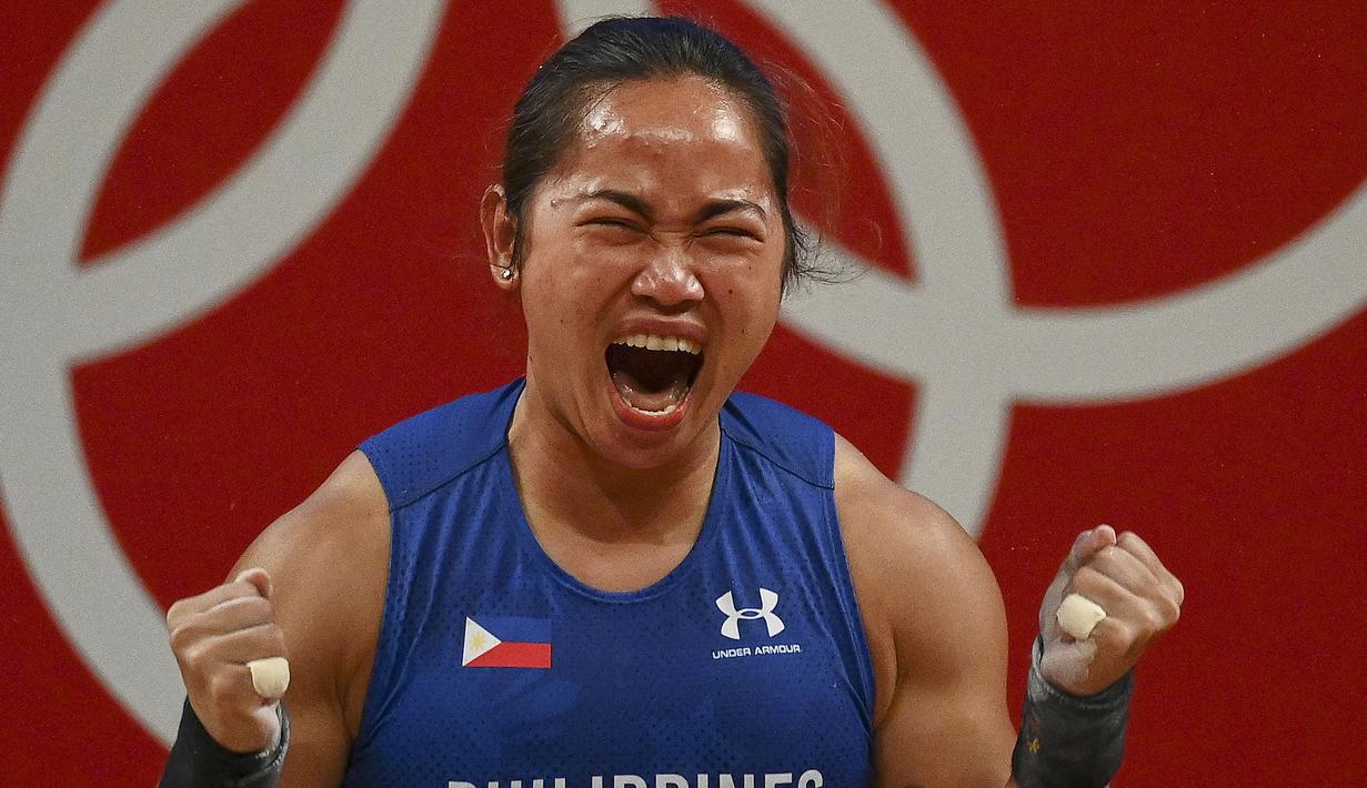 Hidilyn Diaz dari Filipina bereaksi setelah menjadi juara pertama dalam kompetisi angkat besi 55kg putri selama Olimpiade Tokyo 2020 di Tokyo International Forum, Tokyo pada 26 Juli 2021. (AFP/Vincenzo Pinto)