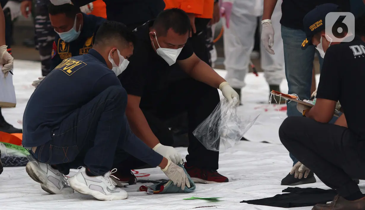 Tim DVI Polri memeriksa serpihan pesawat Sriwijaya Air SJ 182 di Dermaga JICT 2, Jakarta, Minggu (10/1/2021). Tim selam Marinir TNI AL berhasil menemukan dan mengevakuasi serpihan Sriwijaya Air SJ 182 yang kemudian diserahkan ke Basarnas, Kepolisian, serta KNKT. (Liputan6.com/Helmi Fithriansyah)