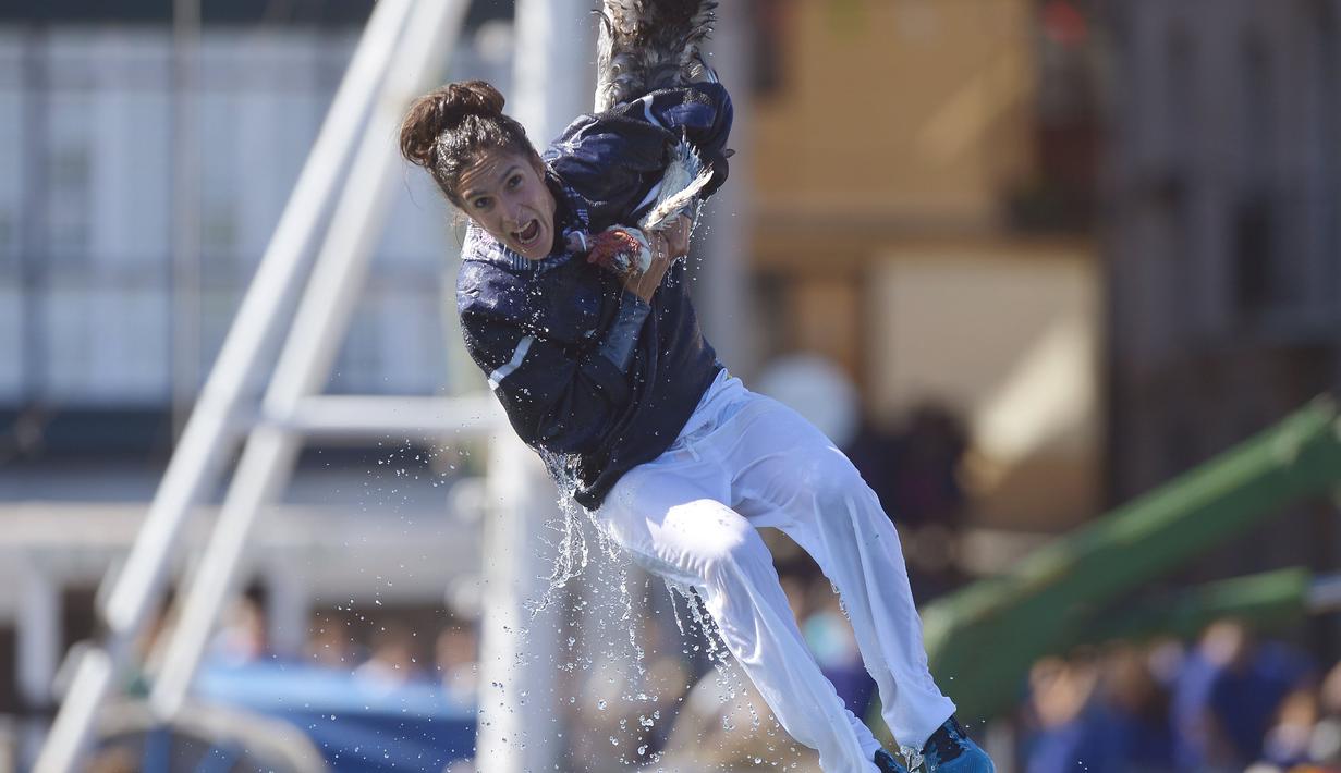 Seorang wanita bergelayutan pada sebuah tali dengan hanya berpegangan pada kepala seekor angsa mati pada Hari angsa atau Antzar Eguna di Spanyol, Minggu (6/9/2015). Festival ini sudah diadakan 350 tahun lalu. (REUTERS/Vincent West)
