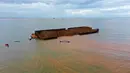 Foto udara menunjukkan perahu nelayan berlayar di sekitaran kapal tongkang pengangkut nikel yang karam dan mencemari laut di perairan tujuan wisata Pantai Gong di Konawe, Sulawesi Tenggara (14/7/2021). Hal tersebut terjadi karena diduga tali kapal tongkang putus saat dihantam ombak besar. (AFP/Ono)