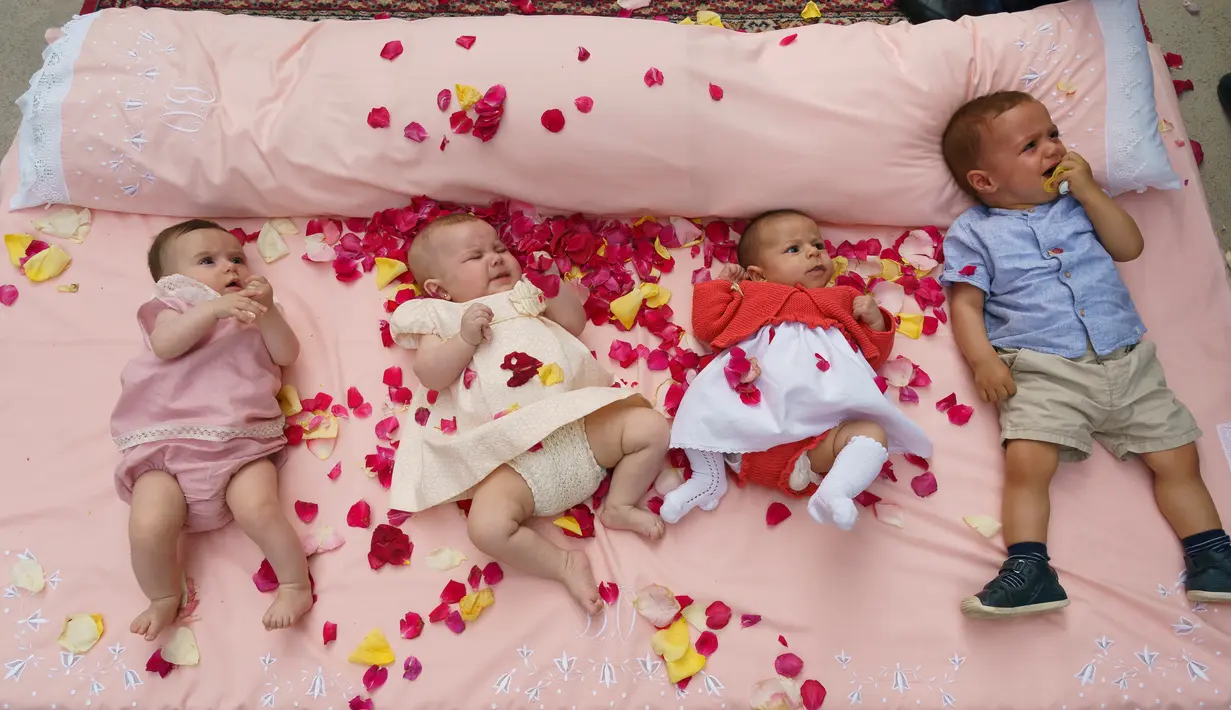 Bayi-bayi ditaburi kelopak mawar sambil terlentang di atas matras untuk dilompati selama festival El Colacho di desa Castrillo de Murcia, bagian utara Spanyol, 23 Juni 2019. Festival melompati bayi ini bermakna untuk membersihkan bayi berusia hingga satu tahun dari roh-roh jahat. (CESAR MANSO/AFP)