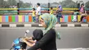 Pejalan kaki melintasi jembatan layang yang dicat dengan warna-warna ceria di Kampung Makasar, Jakarta, Kamis (26/7).  Pengecatan dilakukan guna mempercantik dan menyambut Asian Games 2018 pada Agustus mendatang.  (Liputan6.com/Faizal Fanani)