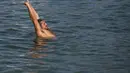 Seorang pria bermain dengan anjingnya di daerah berbatu di pantai Arpoador selama gelombang panas di Rio de Janeiro, Brasil, pada hari libur kota Saint Sebastian, Kamis (20/1/2022). (AP Photo/Bruna Prado)