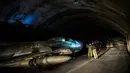 Tentara Albania berjalan di sebelah pesawat tempur MIG-19 dalam terowongan utama Pangkalan Udara Gjader di dekat Kota Lezhe, 5 Februari 2019. Pangkalan Udara Gjader berlokasi dalam perut gunung tandus. (Gent Shkullaku/AFP)