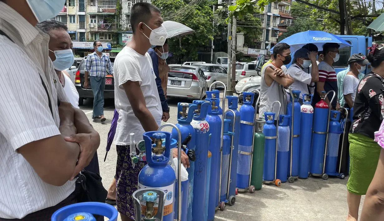 Orang-orang mengantre dengan tabung oksigen mereka di luar stasiun pengisian oksigen di kota Pazundaung di Yangon, Myanmar, Minggu (11/7/2021). Para pejabat mengatakan Myanmar mengalami lonjakan kasus COVID-19, memicu kelangkaan pasokan oksigen yang sangat dibutuhkan pasien. (AP Photo)
