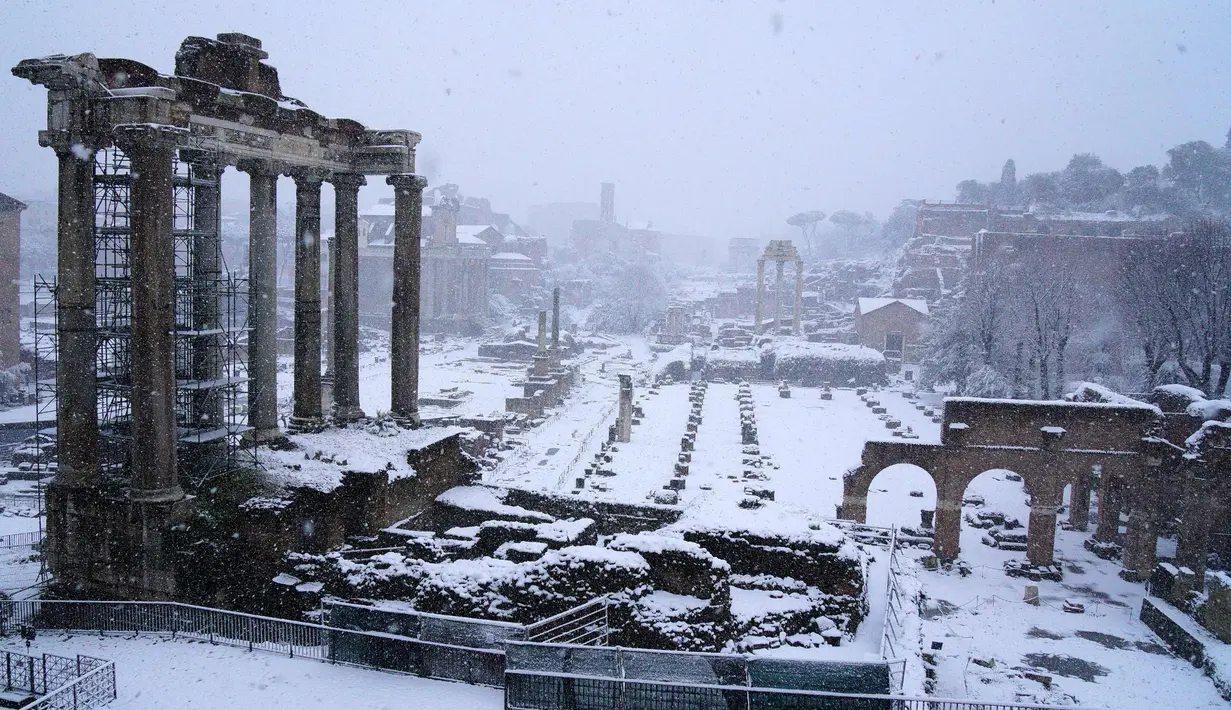 Bangunan kuno yang tertutup salju tebal di Roma, Italia (26/2). Badai salju yang melanda Italia menganggu transportasi dan sekolah diliburkan. (AFP Photo/Vicenzo Pinto)
