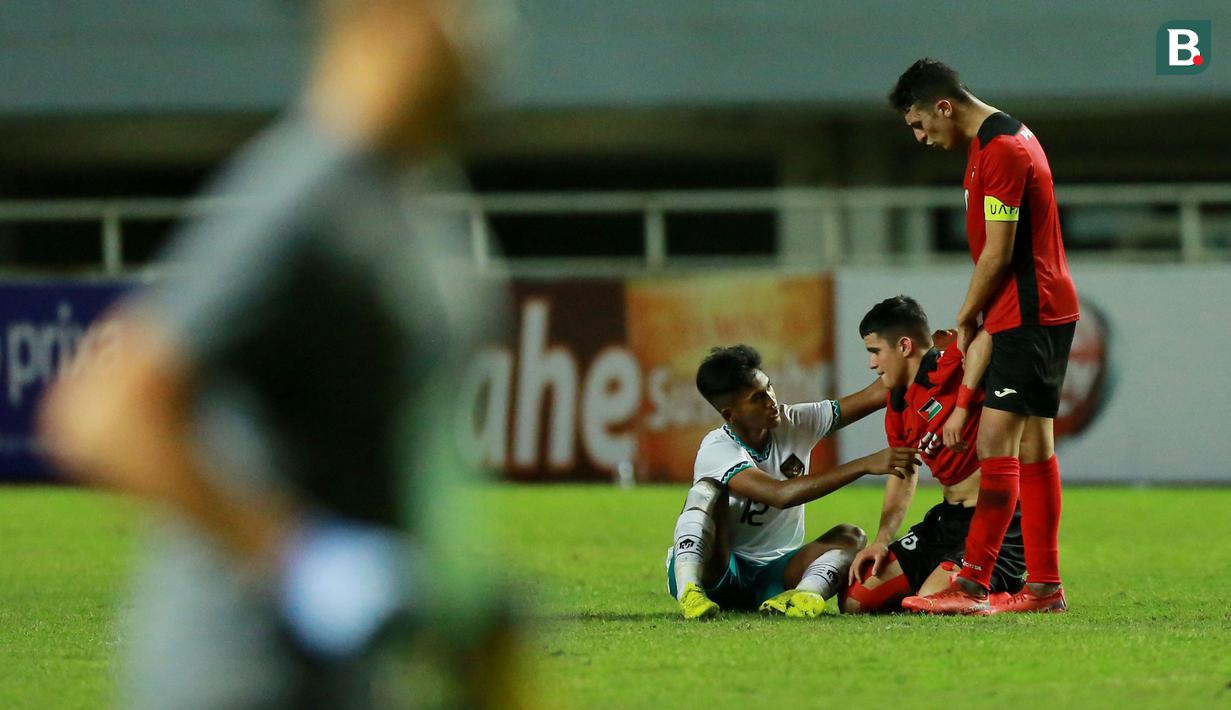 Pemain Timnas Indonesia U-17, Muhammad Narendra Tegar (kiri) berusaha menghibur para pemain Palestina usai berakhirnya laga Grup B Kualifikasi Piala Asia U-17 2023 di Stadion Pakansari, Bogor, Jumat (7/10/2022). (Bola.com/M Iqbal Ichsan)