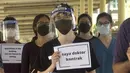 Seorang dokter memegang plakat bertuliskan "Saya seorang dokter kontrak" saat berpartisipasi dalam aksi mogok di Rumah Sakit Sungai Buloh di Selangor, Malaysia, Senin(26/7/2021). Mereka menuntut kondisi yang lebih baik di tengah pandemi virus Corona (COVID-19) yang makin melonjak. (AP Photo)