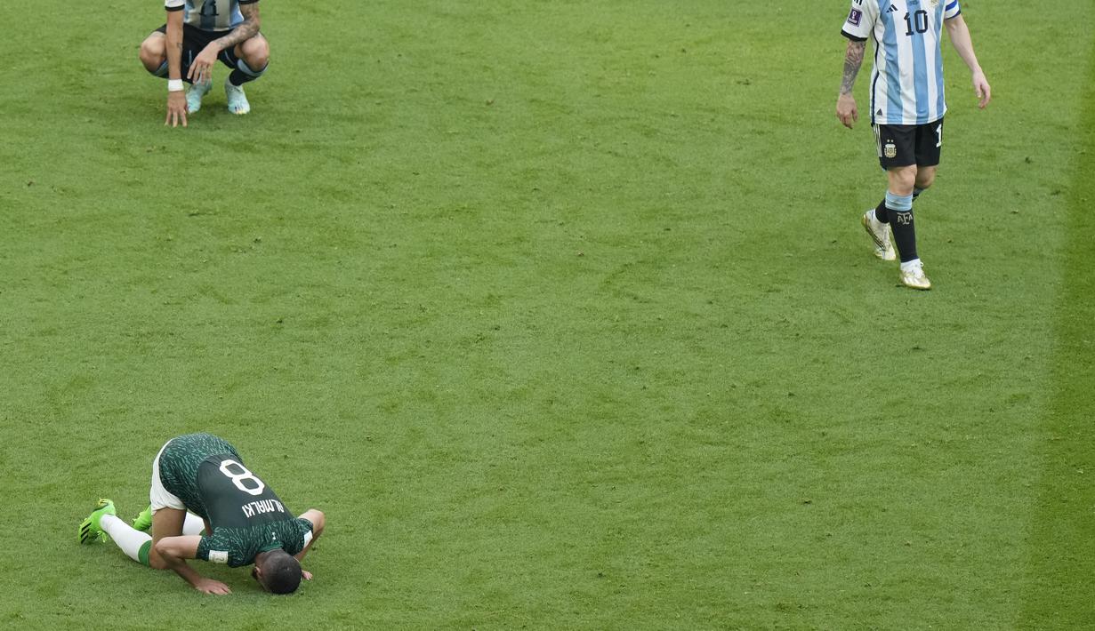 Penyerang Argentina Lionel Messi meninggalkan lapangan saat bek Arab Saudi Mohammed Al-Burayk berselebrasi merayakan kemenangan timnya pada laga pembuka Grup C Piala Dunia 2022 Qatar di Lusail Iconic Stadium, Lusail, Selasa (22/11/2022). Kemenangan Arab Saudi mematahkan rekor Argentina yang selalu menang di pertandingan perdana Piala Dunia selama lebih dari 30 tahun. (AP Photo/Luca Bruno)