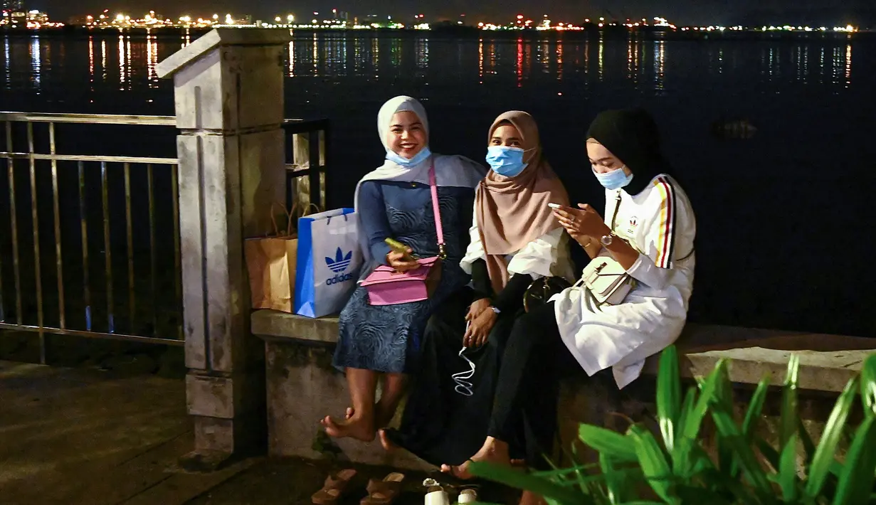 Sejumlah wanita bersantai di tepi perairan di Penang (1/8/2020). Malaysia tengah memperingatkan gelombang kedua virus corona COVID-19. (AFP Photo/Goh Chai Hin)