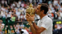 Petenis Swiss, Roger Federer mencium trofi setelah melawan petenis Kroasia, Marin Cilic pada pertandingan final tunggal putra Kejuaraan Wimbledon 2017 di Wimbledon, London. (16/07). Roger Federer menang 6-3, 6-1, 6-4. (AFP Photo / Adrian Dennis)