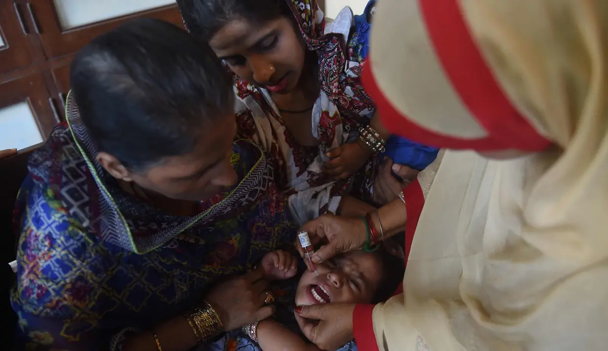 Seorang anak menangis saat diberikan vaksin polio selama kampanye vaksinasi polio di Karachi, Pakistan (9/4). Pakistan adalah salah satu dari hanya dua negara di dunia di mana polio, penyakit masa kecil yang melumpuhkan. (AFP Photo/Rizwan Tabassum)