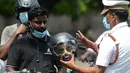 Petugas polisi memegang kepala mockup dengan helm selama kampanye kesadaran keselamatan jalan, di Chennai (7/7/2021). (AFP/Arun Sankar)
