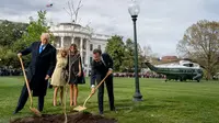 Donald Trump menanam pohon bersama dengan mitranya, Emmanuel Macron pada April 2018 lalu (AP Photo)
