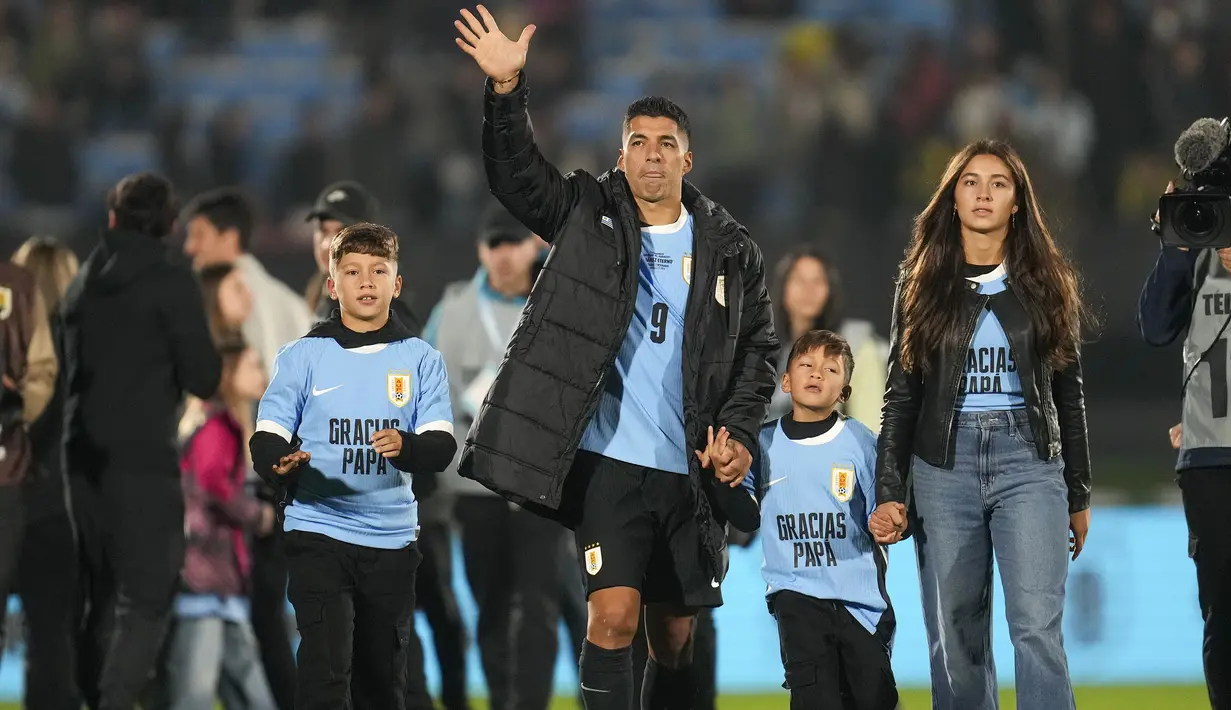 Pemain Uruguay, Luis Suarez (tengah) bersama ketiga anaknya melambaikan tangan kepada para penonton saat acara perpisahannya dengan Timnas Uruguay sebelum laga kualifikasi Piala Dunia 2026 melawan Paraguay yang berlangsung di Stadion Centenario, Montevideo, Uruguay, Sabtu (07/09/2024) WIB. (AFP/Dante Fernandez)