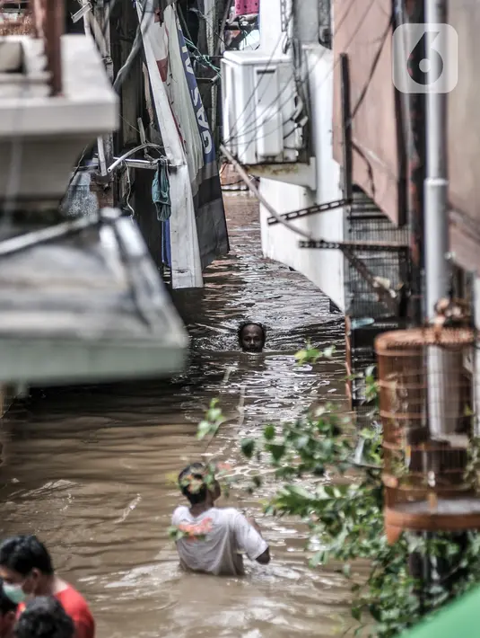 Warga menyusuri banjir yang merendam permukiman di Kebon Pala, Jakarta, Senin (8/2/2021). Banjir di Kebon Pala terus meninggi pada dini hari tadi hingga mencapai ketinggian 2,5 meter.  (merdeka.com/Iqbal S. Nugroho)