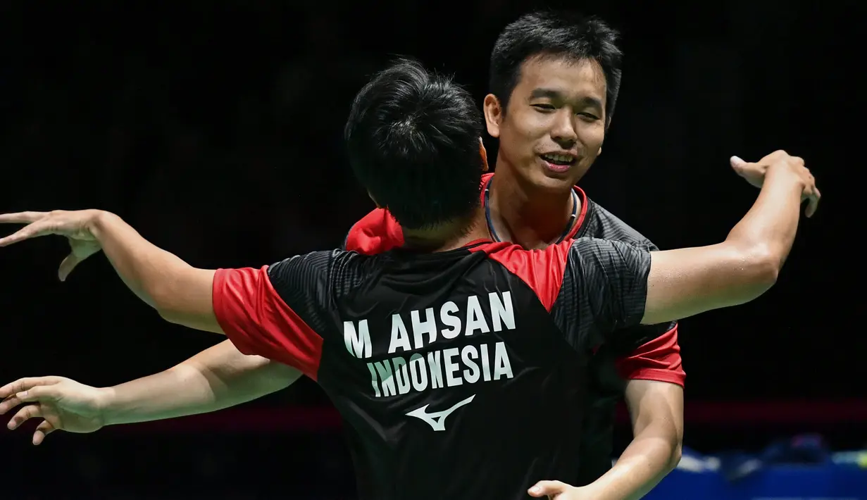 Ganda putra Indonesia Hendra Setiawan (kanan) dan Mohammad Ahsan merayakan kemenangan atas ganda putra Jepang Takuro Hoki dan Yugo Kobayashi pada babak final Kejuaraan Dunia Bulu Tangkis 2019 di Swiss, Minggu (25/8/2019). Ahsan/Hendra menang dengan skor 25-23, 9-21, 21-15. (FABRICE COFFRINI/AFP)