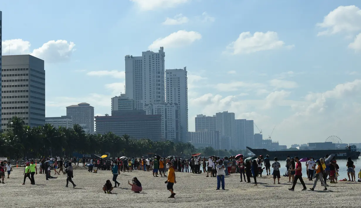 Orang-orang menikmati suasana Manila baywalk dolomite beach di sepanjang boulevard Roxas, kota Manila, Filipina pada Minggu (17/10/2021). Sehari sebelumnya, pihak berwenang melonggarkan pembatasan karantina di ibu kota negara itu. (Ted ALJIBE / AFP)