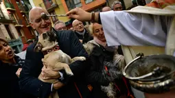 Seorang pria membawa anjingnya untuk diberkati pada peringatan Hari santo Antonius di luar gereja San Nicolas, Spanyol, Kamis (17/1). Pada perayaan tahunan itu, para pemilik membawa hewan peliharaan untuk diberkati oleh pastor. (AP/Alvaro Barrientos)