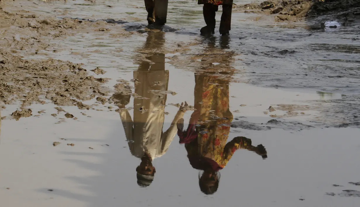 Seorang anak laki-laki dan perempuan tercermin dalam air di dekat rumah mereka yang dilanda banjir, di Charsadda, Pakistan, Rabu (31/8/2022). Para pejabat di Pakistan menyampaikan kekhawatiran Rabu atas penyebaran penyakit yang ditularkan melalui air di antara ribuan korban banjir saat air banjir dari hujan monsun yang kuat mulai surut di banyak bagian negara. (AP Photo/Mohammad Sajjad)