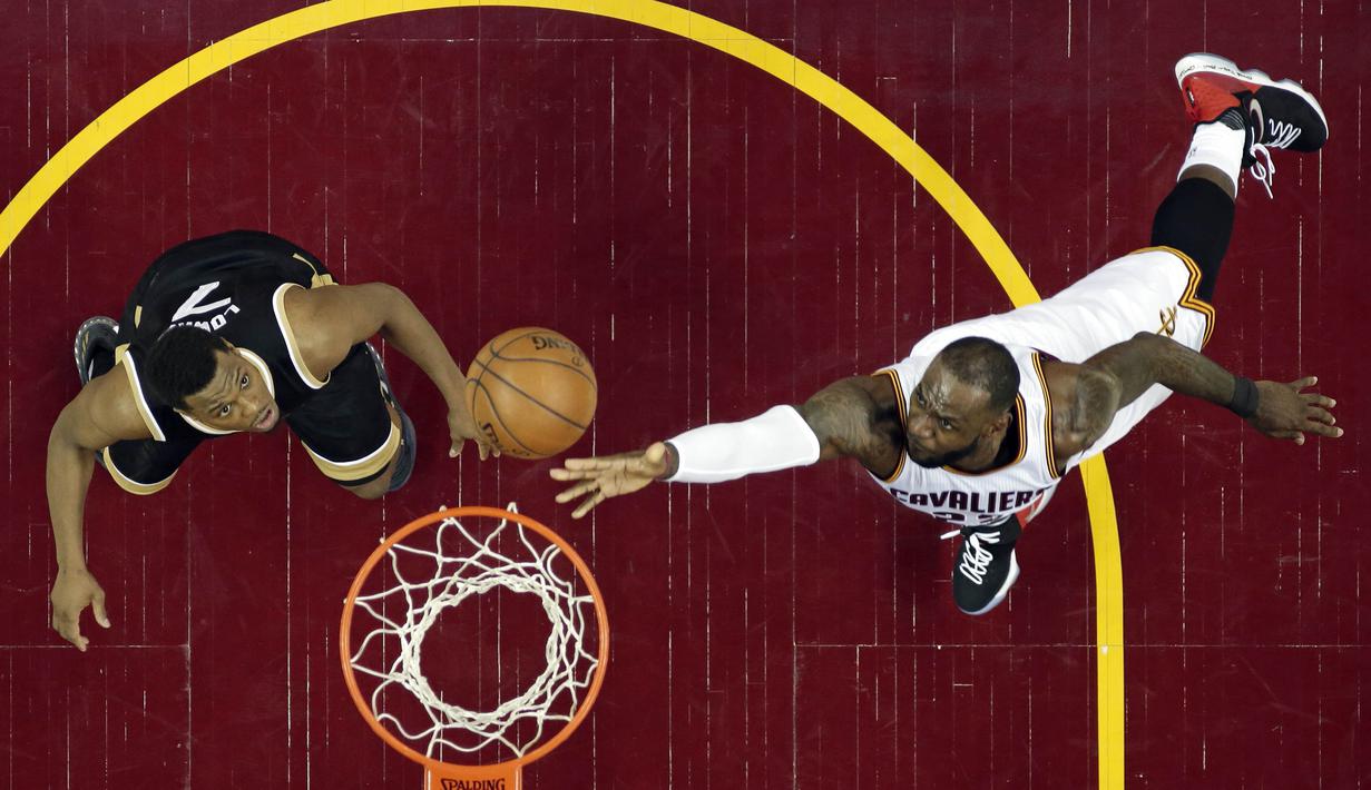 Aksi LeBron James (kanan) memasukan bola melewati adangan pemain Toronto Raptors, Kyle Lowry pada Game 2 pada semifinal Eastern Conference NBA basketball playoff series di Quicken Loans Arena, (3/5/2017). Cavs menang 125-103. (AP/Tony Dejak)