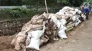 Pekerja membangun turap di bantaran Kali Setu Babakan, Jakarta, Sabtu (27/10). Turap dari tanah dan batu yang dimasukkan ke karung itu dibuat guna mencegah longsor yang sudah beberapa kali terjadi di kawasan tersebut. (Liputan6.com/Immanuel Antonius)