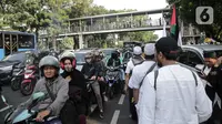 Peserta aksi reuni 212 berjalan saat kendaraan terjebak kemacetan di kawasan Jalan Thamrin dan Merdeka Barat, Jakarta, Senin (2/12/2019). Sejumlah ruas jalan di Jakarta mengalami kemacetan parah akibat aksi reuni 212 di kawasan Monas. (Liputan6.com/Faizal Fanani)