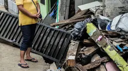 Warga melihat rumah yang roboh akibat pembuatan saluran air di Jalan Kayu Manis IX, Matraman, Jakarta Timur, Senin (16/12/2019). Pelaksana pembangunan saluran air akan bertanggung jawab memperbaiki rumah yang telah lapuk fondasinya tersebut mulai Senin. (Liputan6.com/Faizal Fanani)