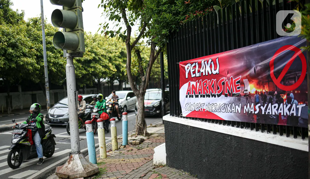 Pengendara motor melintas di dekat spanduk imbauan tolak anarkisme di Jakarta, Minggu (11/10/2020). Spanduk imbauan untuk tidak melakukan aksi anarkisme merebak di sejumlah kawasan di Jakarta pascaaksi unjuk rasa massa yang menolak pengesahan Omnibus Law UU Cipta Kerja. (Liputan6.com/Faizal Fanani)